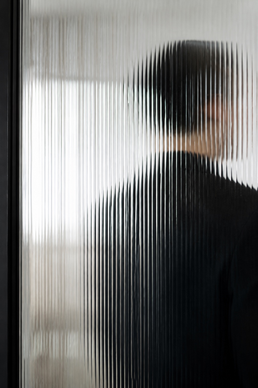 A person seen through textured glass, keeping their identity private